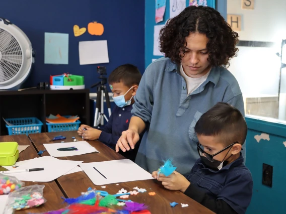 young teacher crafting at a table with to children