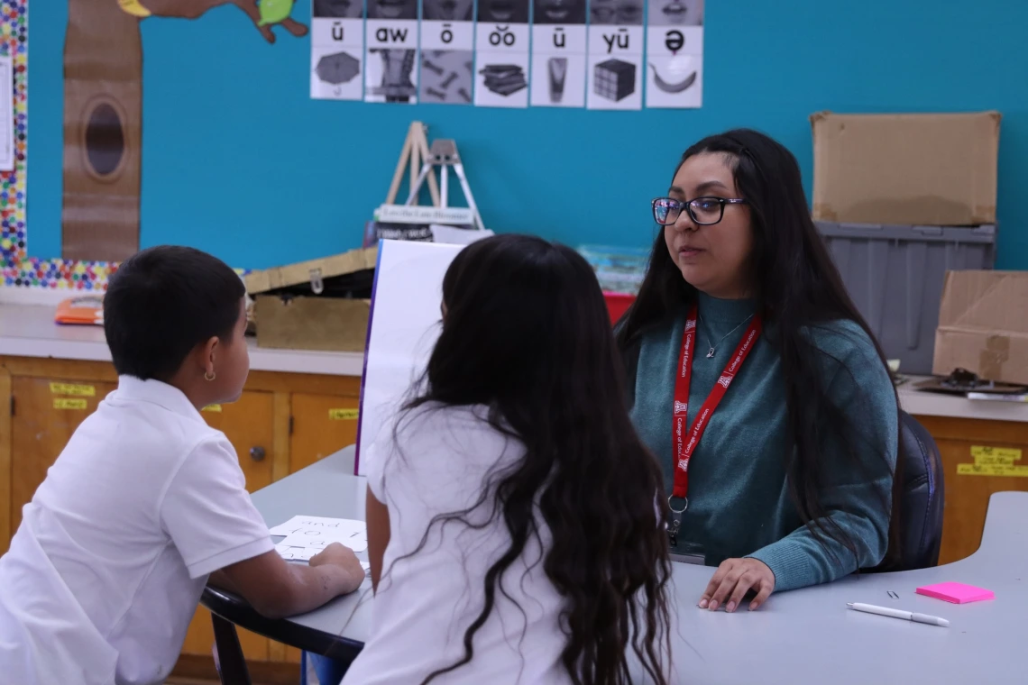 words cats math cats.jpg educator sitting at a table with two young students in a classroom